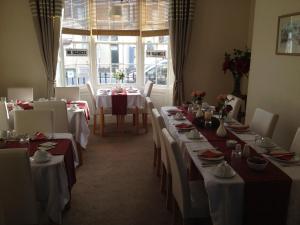 una sala da pranzo con tavoli bianchi e sedie bianche di Arcadia Guest House a Weymouth