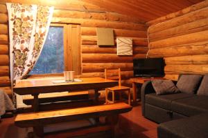 Cabaña de madera con sala de estar con mesa y sofá en Mökki Cottages RukaTupa en Ruka