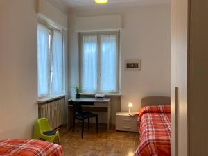 een slaapkamer met 2 bedden, een bureau en een raam bij Casa I Tre by Holiday World in Cuneo