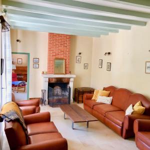 a living room with leather couches and a fireplace at Domaine de l'Augeonnière in Villandry