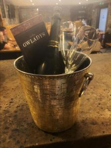 a metal bucket with a bottle of wine and glasses at Sgwd Gwladys Lodge in Pont-Nedd-Fechan