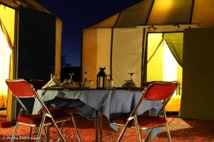 a table and four chairs with a table and a tent at Ouzina Desert Camp in Ouzina