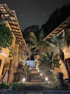 a building with stairs and palm trees at night at Villa Garoupeta - Apartamentos in Bombinhas