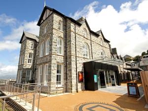 a large stone building with a clock on it at Harlech Apartments - Efnisien in Harlech