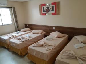 een kamer met drie bedden in een kamer bij Luz do Mundo Hotel in Aparecida
