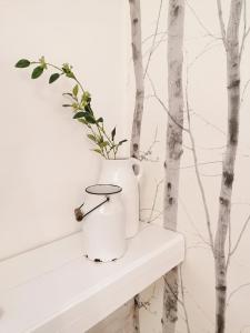 a white vase sitting on a white shelf with trees at Jászberény Boutique Room in Jászberény