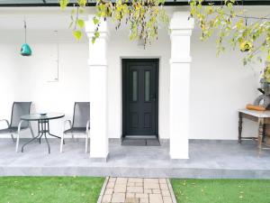 a black door on a white house with chairs and a table at Jászberény Boutique Room in Jászberény