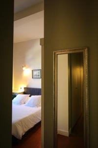 a mirror next to a bed in a bedroom at Les Chambres d'Andrea in Marseillan