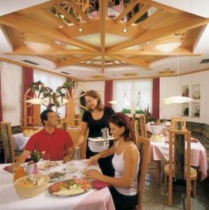 un grupo de personas sentadas en una mesa en un restaurante en Hotel Residence Lorenz en Colle Isarco