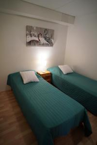 2 camas en una habitación con sábanas verdes en RukanEtelärinne H, en Ruka