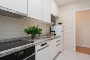 cocina blanca con fregadero y nevera en Lovely Bright Flat - Instaworthy City View, en Vila Nova de Gaia