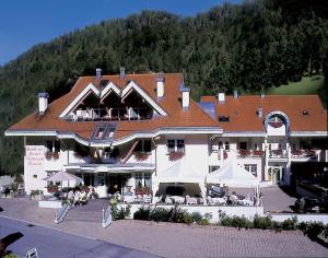 un grande edificio con persone sedute fuori di Hotel Residence Lorenz a Colle Isarco