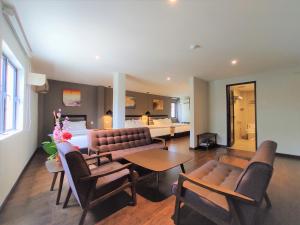 a living room with a couch and chairs and a bed at Apple Suites Hotel in Sitiawan