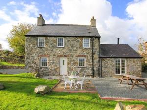 a stone house with a table and chairs in front of it at Ty Capel Bryntwrog in Holyhead