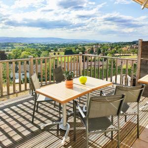 einen Holztisch und Stühle auf einer Terrasse mit Aussicht in der Unterkunft gite horizon in Neulise