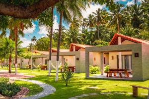 a house with palm trees in front of it at Costa Dourada Village in Maragogi