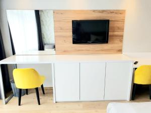 einen weißen Schreibtisch mit einem TV und 2 gelben Stühlen in der Unterkunft Haus am See Luxury HS 948 in Hahnenklee-Bockswiese