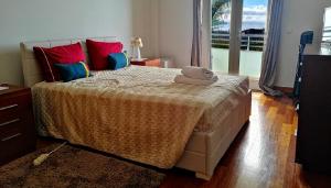 フンシャルにあるColinas do Solのベッドルーム1室(大型ベッド1台、赤と青の枕付)