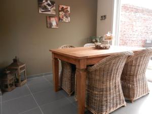cocina con mesa de madera y sillas de mimbre en Holiday Home Juliette, en Poperinge