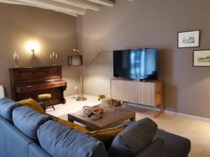 sala de estar con sofá azul y TV en Villa Sainte-Marie - Les Bastides d'Edouard - Chablis, en Maligny