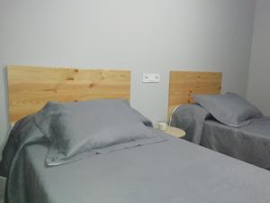 sypialnia z białym łóżkiem i drewnianym zagłówkiem w obiekcie Ecorooms PADRÓN w mieście Padrón