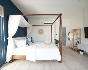 um quarto com uma cama de dossel com lençóis brancos em Wayla Villa@Maikhaobeach em Praia de Mai Khao