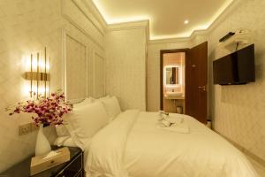 a bedroom with a white bed with a tv and flowers at AJ Residence - Above Peppermint Asia City in Kota Kinabalu