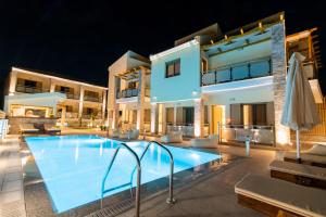 a villa with a swimming pool at night at Melydron Apartments in Preveza