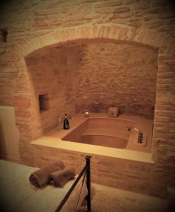 La salle de bains est pourvue d'une grande baignoire et d'un mur en pierre. dans l'établissement La Scalinata Apartment, à Pérouse