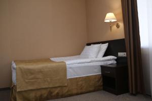 - une chambre avec un lit doté de draps blancs et d'une lampe dans l'établissement Hotel Aner, à Astana