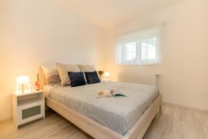 a white bedroom with a large bed with blue pillows at Apartmány Jedovary in Trhové Sviny