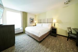 a hotel room with a bed and a desk and a window at Candlewood Suites Columbus-Northeast, an IHG Hotel in Columbus