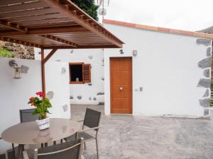 a patio with a table and chairs and a wooden door at CASA BIBIANA CON ESPECTACULARES VISTAS in Hermigua