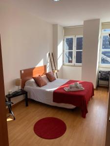 um quarto com uma cama com um cobertor vermelho e 2 janelas em Formosa Oporto Apartments Group no Porto