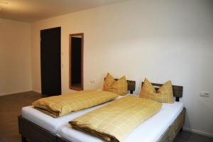 a bedroom with two beds with yellow and orange pillows at Herberge Bärenschenke in Meßkirch