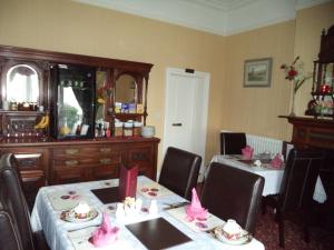 a dining room with two tables and chairs with pink decorations at Britten House in Lowestoft