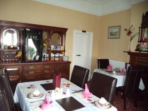 een eetkamer met 2 tafels en stoelen met roze decoraties bij Britten House in Lowestoft