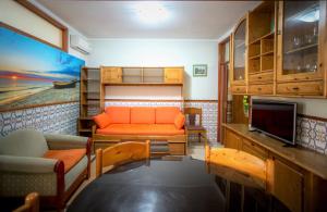 a living room with an orange couch and a tv at Atlantico Sul in Quarteira