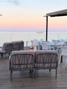 eine Gruppe von Stühlen und Tischen auf einer Terrasse mit Meerblick in der Unterkunft Hôtel Calavita Rooftop & Spa in Bastia