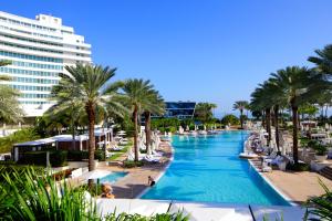 a swimming pool with palm trees and a hotel at FB Miami Beach Tresor Private Luxury Suites in Miami Beach