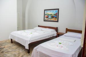 two beds in a room with white sheets at Pousada Porto das Barcas in Parnaíba