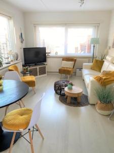 Una sala de estar con un sofá y sillas y un televisor. en De Kneet, en Egmond aan Zee