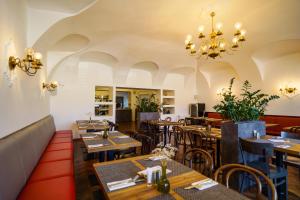 a restaurant with wooden tables and chairs and a chandelier at Hotel U Labutě in Žďár nad Sázavou