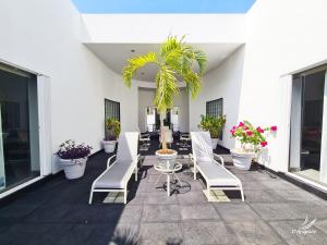 un patio con sillas blancas, una mesa y plantas en Almarea Vacation Condo en Playa del Carmen