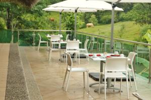 a patio with white tables and chairs and an umbrella at Hotel Villa Mercedes Palenque in Palenque