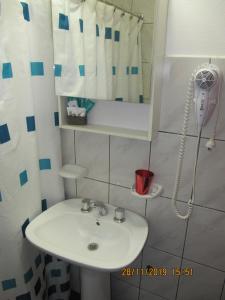y baño con lavabo blanco y ducha. en Apart Casas Del Centro en El Calafate