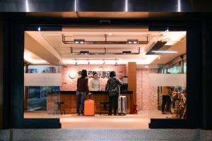 two people standing in a store window with luggage at Kiwi Express Hotel - Chenggong Rd in Taichung