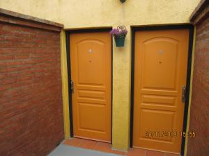 dos puertas naranjas en un edificio con una maceta de flores en Apart Casas Del Centro en El Calafate