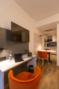 a kitchen with a desk with a laptop and orange chairs at Boardinghouse Hirsch - Apartments in Kork in Kehl am Rhein