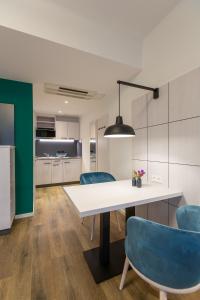 a kitchen and dining room with a white table and blue chairs at Boardinghouse Hirsch - Apartments in Kork in Kehl am Rhein
